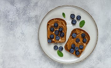 Rye bread with peanut paste and fresh blueberries, top view, no people