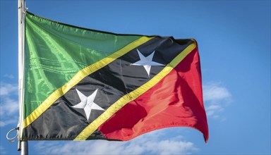 The flag of St Kitts, Caribbean, fluttering in the wind, isolated against a blue sky