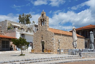 Stone church with café terrace under a partly cloudy blue sky in a relaxed setting, Church of St