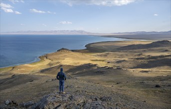 Tourist standing on a hill, view of mountain lake Song Kul, Naryn region, Kyrgyzstan, Asia