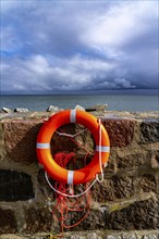 The city harbour of Sassnitz, island of Rügen, pier, harbour dam, dark rain clouds, lifebuoy,