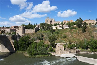 Landscape with river and bridge, in the background a castle and various buildings under a blue sky