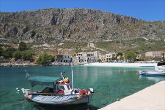 Fishing boat in a quiet harbour in front of a steep mountain landscape in sunny weather,