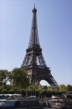 The Eiffel Tower in Paris, flanked by trees, with boats in the foreground, Paris