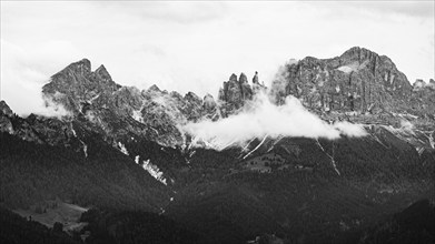 The peaks of the rose garden, shrouded in mist, drone shot, black and white image, Dolomites,