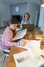 Homeschooling, during the lockdown in January 2021, children learn at home for school, their mum is