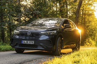 Front view of a car on a road in the forest during sunset, electric car, VW ID5, Gechingen, Black