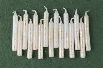 White candles with golden decoration arranged on a green background