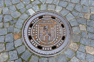 Manhole cover with Liberec city coat of arms, surrounded by cobblestones, manhole cover, Liberec,