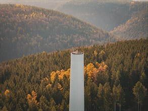 Autumn coloured hill with a wind turbine, surrounded by forest, wind turbine construction,