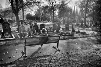 Elderly woman sitting on bench, looking at grave, graves, Tauer, loneliness, black and white,