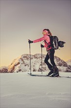 A woman's ski tour at sunrise on the Tegelberg in the Allgäu in the Ammergebirge, Bavaria, Germany,