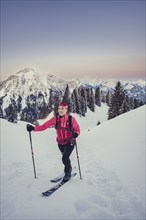 A woman's ski tour at sunrise on the Tegelberg in the Allgäu in the Ammergebirge, Bavaria, Germany,