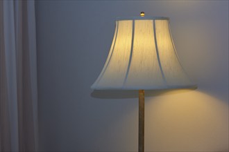 A warmly illuminated bedside lamp with a white shade, cosy