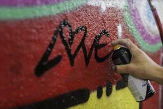 A man sprays graffiti on a wall with a spray can. Berlin, 14.08.2024