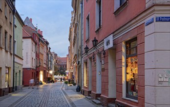 Shop windows illuminated in the evening on Szewska Street in the medieval Old Town of Thorn. The