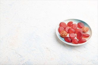 Jelly tomato candies on white concrete background. copy space, side view, close up