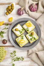 Green cracker sandwiches with cream cheese and cherry tomatoes on white wooden background and linen