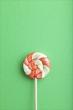 Single lollipop candy on green pastel background. copy space, top view, flat lay