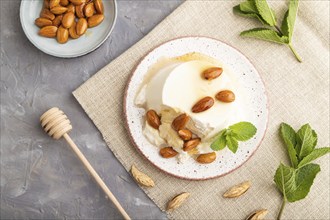 Ricotta cheese with honey and almonds on gray concrete background and linen textile. top view, flat