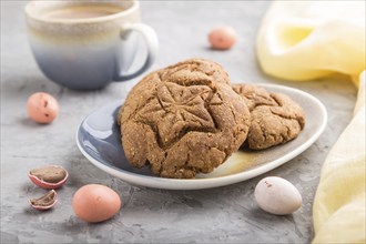 Homemade oatmeal cookies with a cup of cocoa and a yellow textile on a gray concrete background.