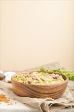 Lentils porridge with champignons and coriander in a wooden bowl on a white and orange background