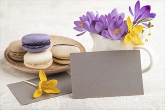 Gray paper business card mockup with spring snowdrop crocus flowers and multicolored macaroons on