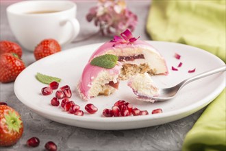 Pink mousse cake with strawberry and a cup of coffee on a gray concrete background and green