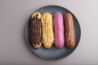 Set of eclair, traditional french dessert on blue ceramic plate on gray pastel background. top