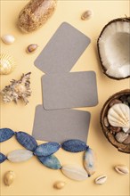 Brown paper business card with coconut, seashells, pebbles, beads on orange pastel background. Top