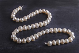 Caramel colored pearl beads on a black background. top view, close up