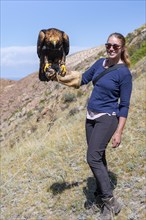 Young tourist with an eagle on her hand, near Kysyl-Suu, Issyk Kul, Kyrgyzstan, Asia