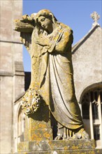 Statue on grave in graveyard of Church of Saint Bartholomew, Corsham, Wiltshire, England, UK