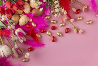 Arrangement in pink and red of flowers, feathers and Easter eggs on a pink background