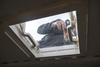 Cutting through roof of white metal camper van conversion to install ventilation window, UK