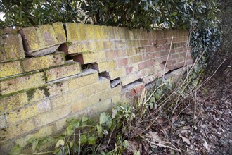 Impact damage to red brick garden wall caused by vehicle reversing, Suffolk, England, UK