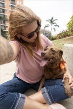 A selfie of a woman looking at her pet, a brown-furred dog with a bindi on its third eye, sticking