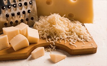 Grated cheese, Maasdam, on a cutting board, grater and cheese knife, close-up, no people