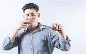 Person with gingivitis holding toothbrush isolated. Man suffering from gum pain holding toothbrush.