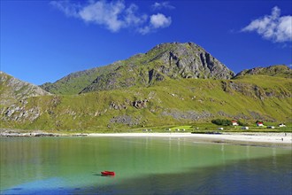 Crystal clear sandy beach with turquoise green water and a green boat, Haukland Strand, Leknes,