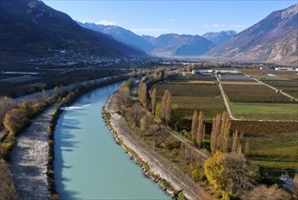 The wide river valley of the canalised Rhone, view downstream towards Martigny, with orchards on