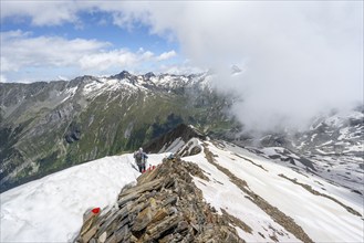 Mountaineer on a rocky ridge with snow, descent from the summit of Schönbichler Horn, view of