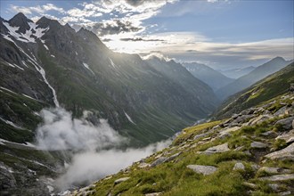 Atmospheric mountain landscape, clouds forming in a mountain valley in the evening light,