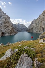 Tourist at the blue mountain lake between rocky steep mountain peaks, Kol Suu Lake, Sary Beles