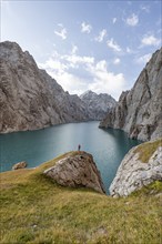 Tourist at the blue mountain lake between rocky steep mountain peaks, Kol Suu Lake, Sary Beles