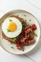 Breakfast, fried egg with bacon, micro-green, on a light background, no people, selective focus