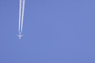 Airbus aircraft of Qatar airways flying across a blue sky with a vapour trail or contrail behind,