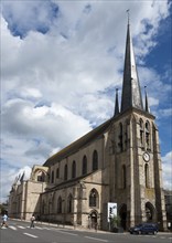 Alte Kirche mit hohem Turm unter einem teilweise bewölkten Himmel an einer Straße, Kirche, Église