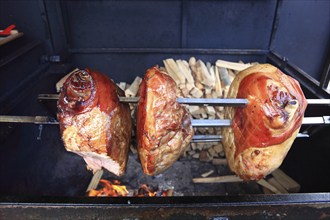 Pork knuckles are grilled on a spit over a wood fire