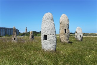 Stone formations in a meadow with a building in the background, under a clear blue sky, Menhires